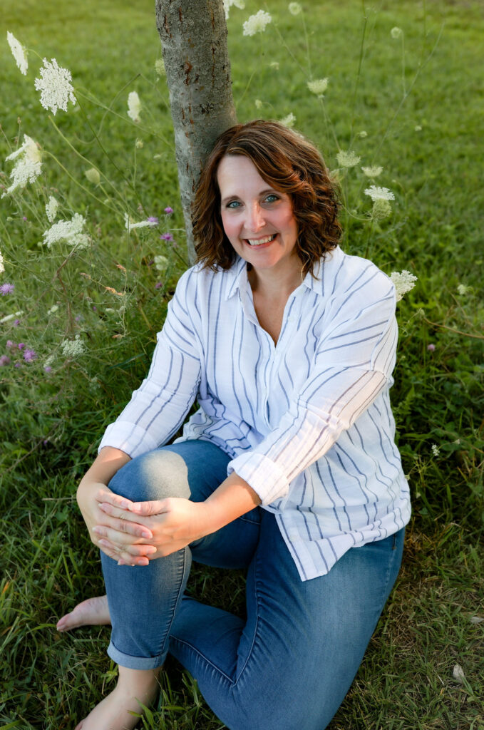 Jamie Eggers sitting outdoors beside a tree